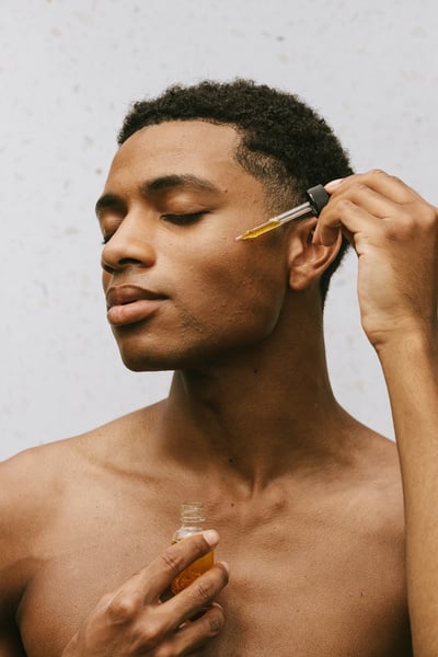 Shirtless Man Applying Serum on Face